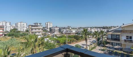 A balcony with a view of a residential area, including buildings and palm trees.
