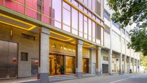 A hotel with a modern facade, large glass windows, and a prominent entrance with a golden sign. - Royal Dragon Hotel (Macau)