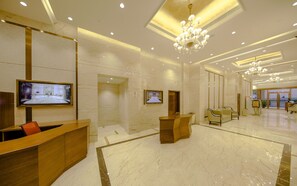 A modern hotel lobby with marble flooring, wooden reception desks, and a large chandelier. - Royal Dragon Hotel (Macau)