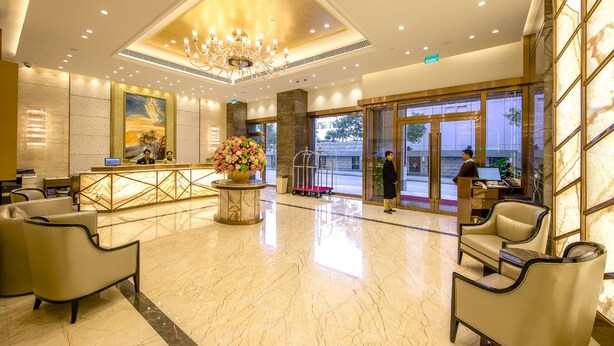 A hotel lobby with a reception desk, seating area, and a large chandelier. - Royal Dragon Hotel (Macau)