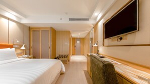 A hotel room with a bed, a desk with a chair, a TV, and a bathroom with a shower. - Royal Dragon Hotel (Macau)