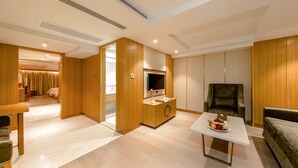 A modern hotel room with a wooden interior, a dining area with a table and chairs, and a seating area with a sofa. - Royal Dragon Hotel (Macau)