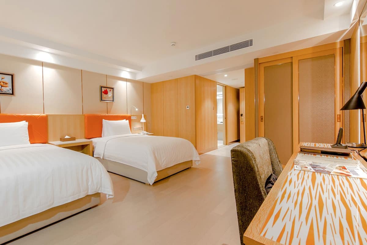 A hotel room with two beds, a desk, and a chair.