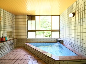 Un baño con suelo de baldosas, bañera, ventana y zona de ducha.