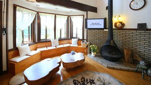 A cozy room with a fireplace, seating area, and a television displaying a message. - Chalet La Neige (Minakami)