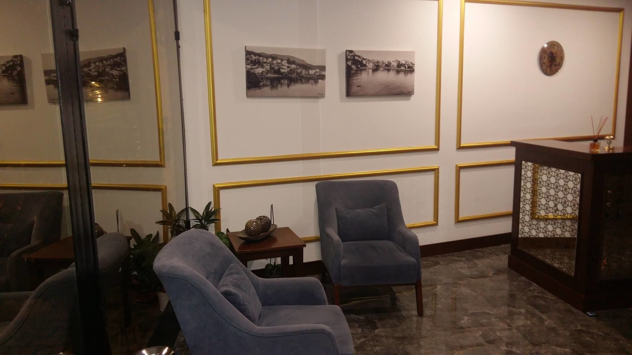 A lobby with two armchairs, a small table with a decorative bowl, and framed black-and-white landscape paintings on the wall.