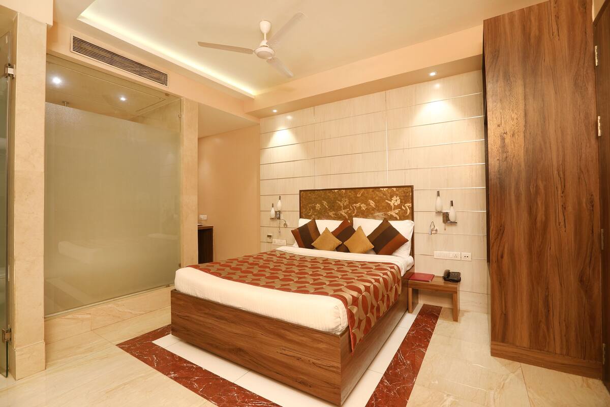 A modern bedroom with a large bed, a wooden wardrobe, and a glass shower enclosure.