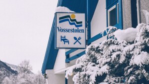 Un letrero con el nombre 'Vossstølen' y símbolos que indican restaurante y alojamiento.