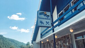 Un edificio con un letrero que dice "Vossestølen" y una vista de la montaña al fondo.