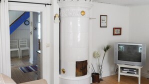 A living room with a white cylindrical heater, a television on a stand, and a staircase in the background. - 1 bedroom cozy home in Jönköping (Jönköping)