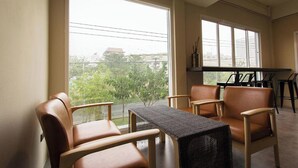 A room with large windows, a piano, and leather chairs. - Lazy Sunday Hostel (Bangkok)