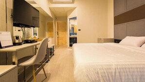 A hotel room with a bed, a desk with a chair, a flat-screen TV, and a window with blue-tinted glass. - Lazy Sunday Hostel (Bangkok)