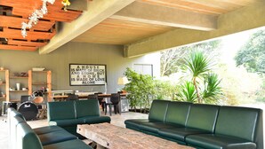 A modern lounge area with green leather sofas, a wooden coffee table, and a drum set in the background. - Home Elements Khaoyai (Pak Chong)