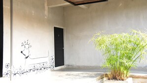 A room with a concrete wall, a black door, and a potted plant. - Home Elements Khaoyai (Pak Chong)