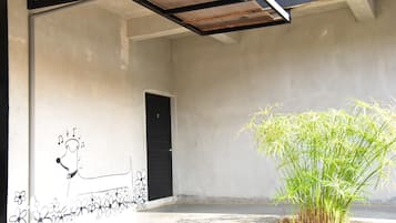 A room with a concrete wall, a black door, and a potted plant.