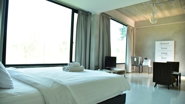 A modern hotel room with a large bed, a desk, and a TV. - Home Elements Khaoyai (Pak Chong)