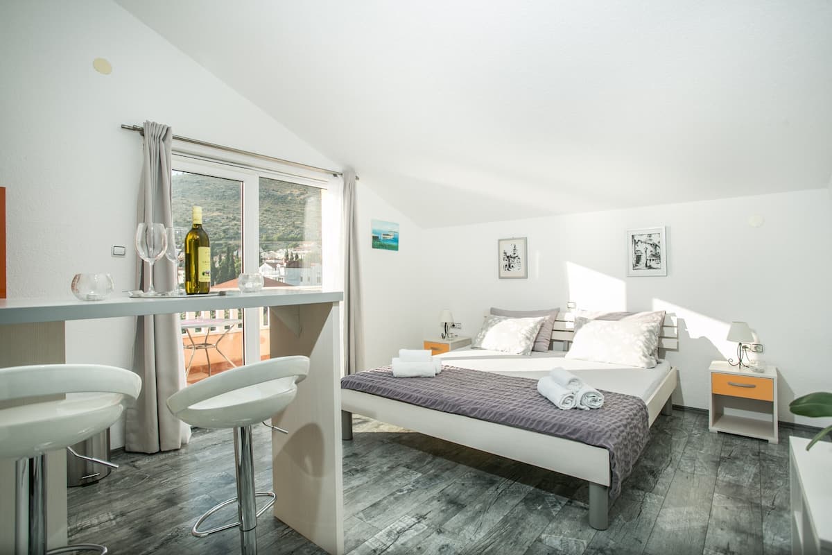 A bedroom with a bed, bedside tables, a desk with a chair, and a window.