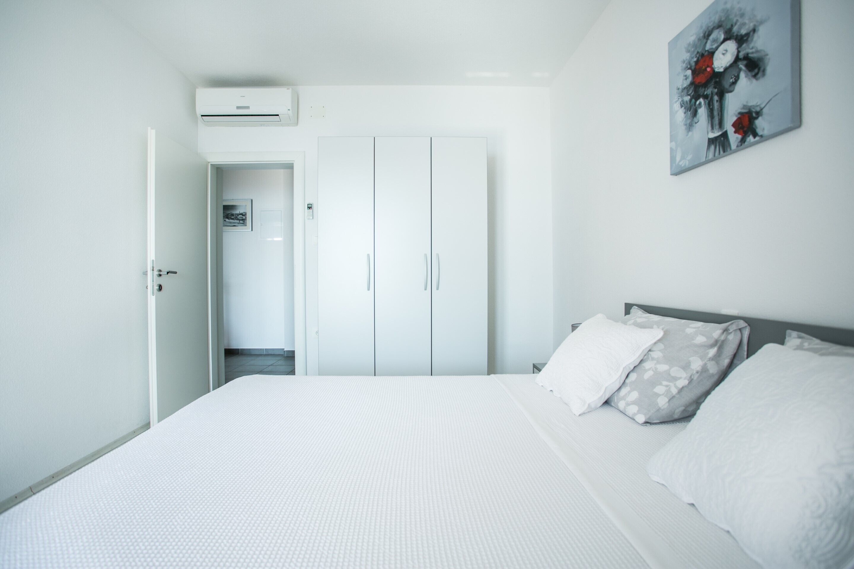 Una camera da letto con un letto, un'armadio bianco e un quadro appeso al muro.
