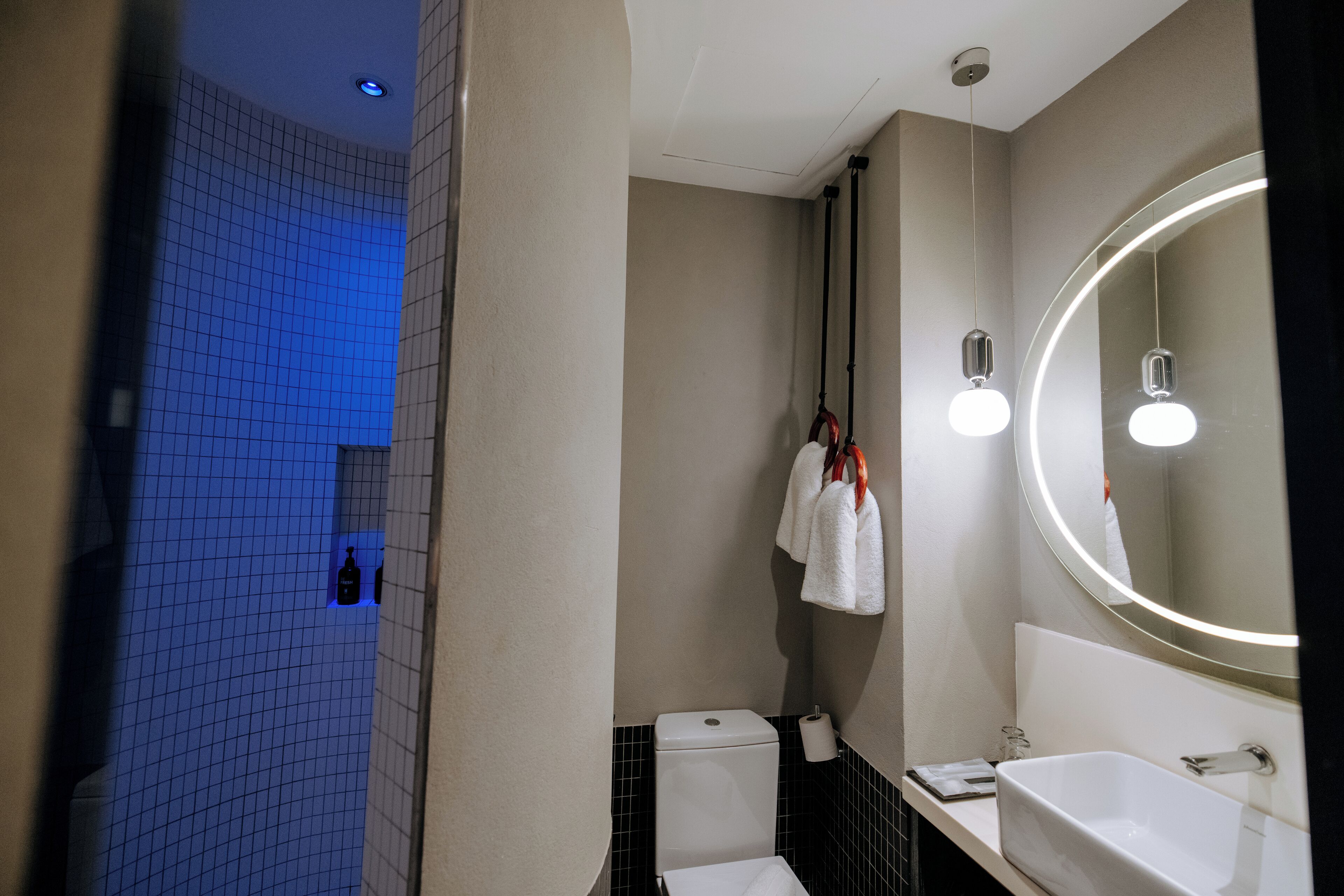 Un baño moderno con un lavamanos blanco, un espejo grande y un inodoro.