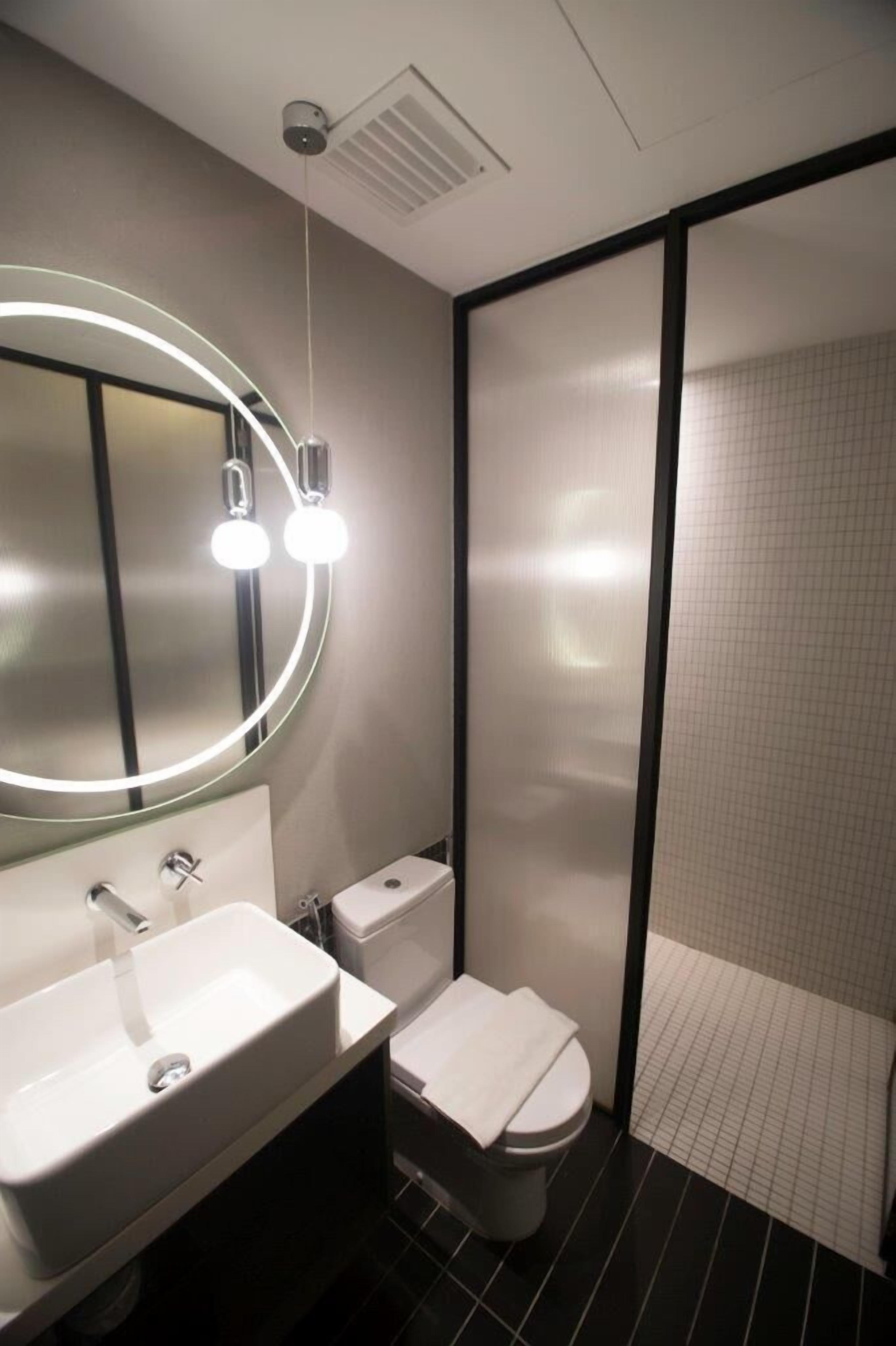 A modern bathroom with a white sink, a toilet, and a shower area.