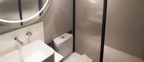 A modern bathroom with a white sink, a toilet, and a shower area.