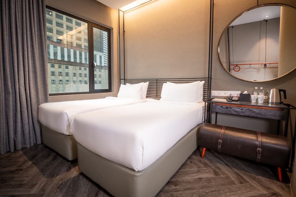 Een hotelkamer met een groot bed, een bureau met spiegel en uitzicht op een gebouw.