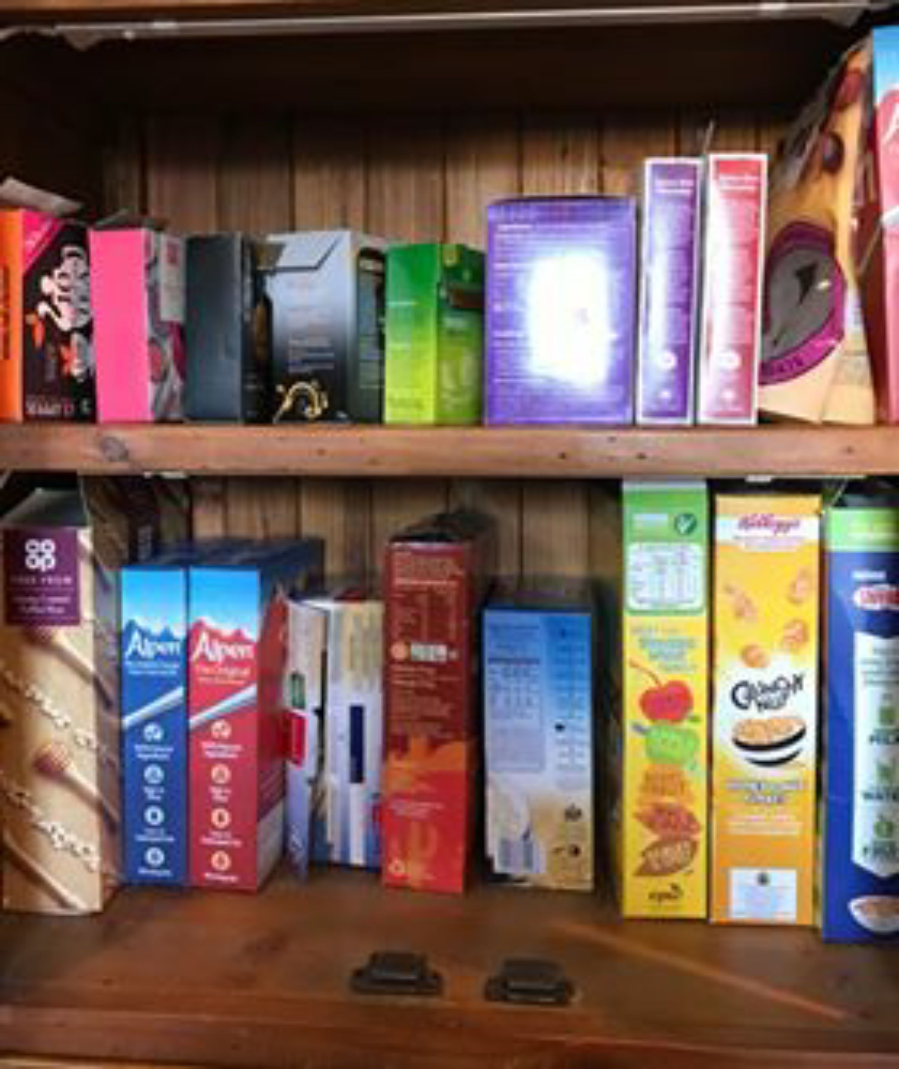 A shelf stocked with various food products including cereals, snacks, and beverages.