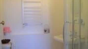 A bathroom with a toilet, a shower enclosure, and a window with blinds.