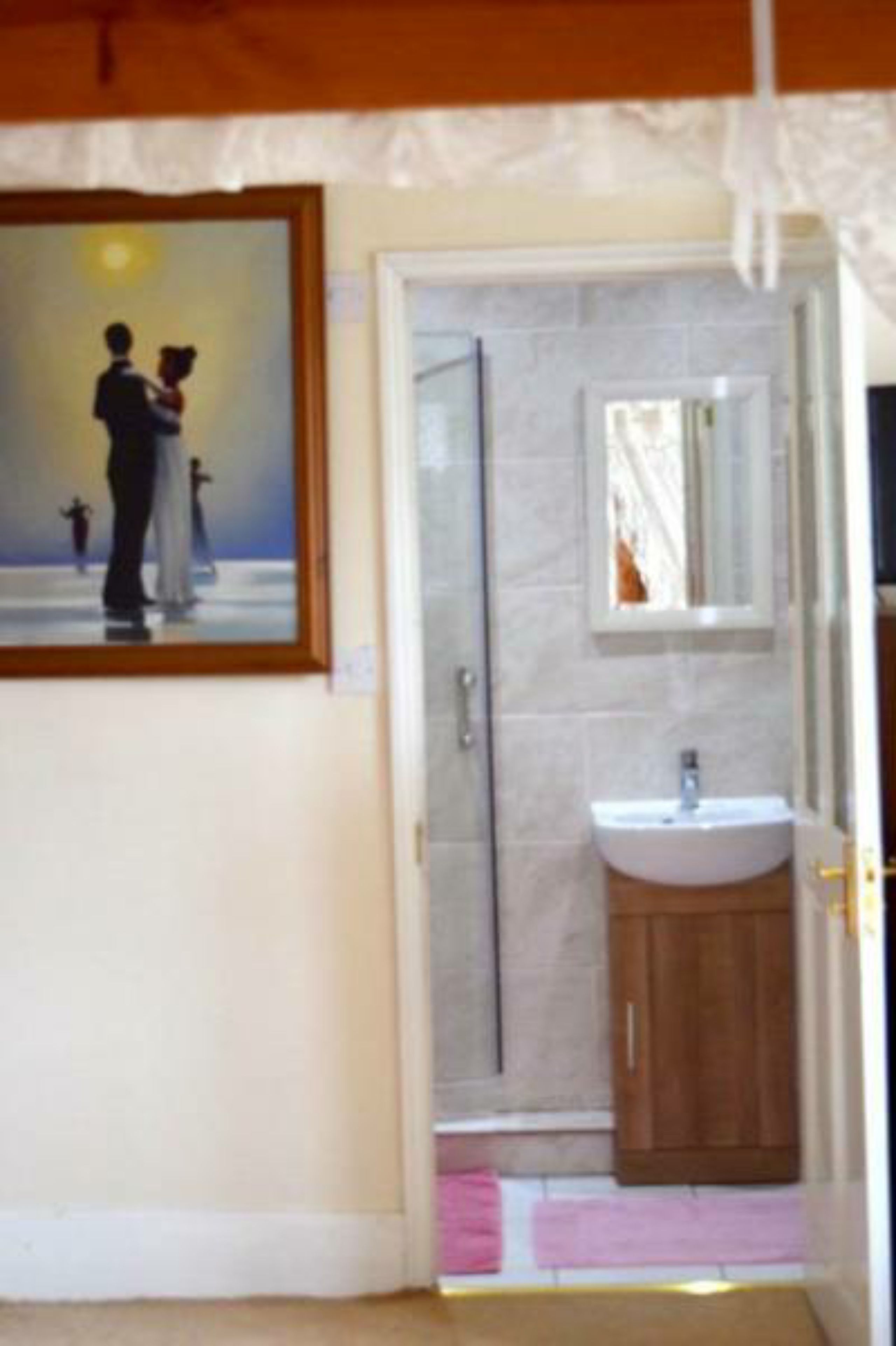 Une salle de bain avec un lavabo, un miroir et un tableau encadré accroché au mur.