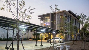A modern building with a covered outdoor area, a car parked in front, and a sign indicating a restaurant. - Nai-Ya-Place (Kanchanaburi)