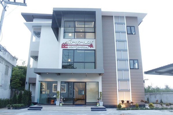 A modern building with a glass storefront, a sign reading "New Year Place," and a staircase leading to the entrance.