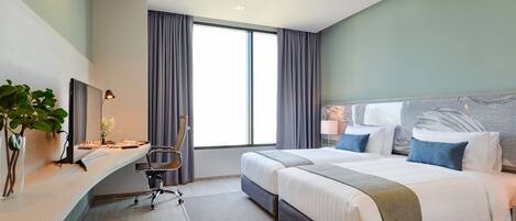 A modern hotel room with a large bed, a desk with a chair, a television, and a large window with curtains.