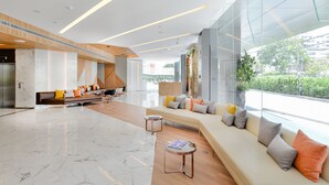 Un hall espacioso con un diseño moderno, que cuenta con una amplia zona de estar, un revestimiento de madera y un gran ventanal con vistas al exterior.