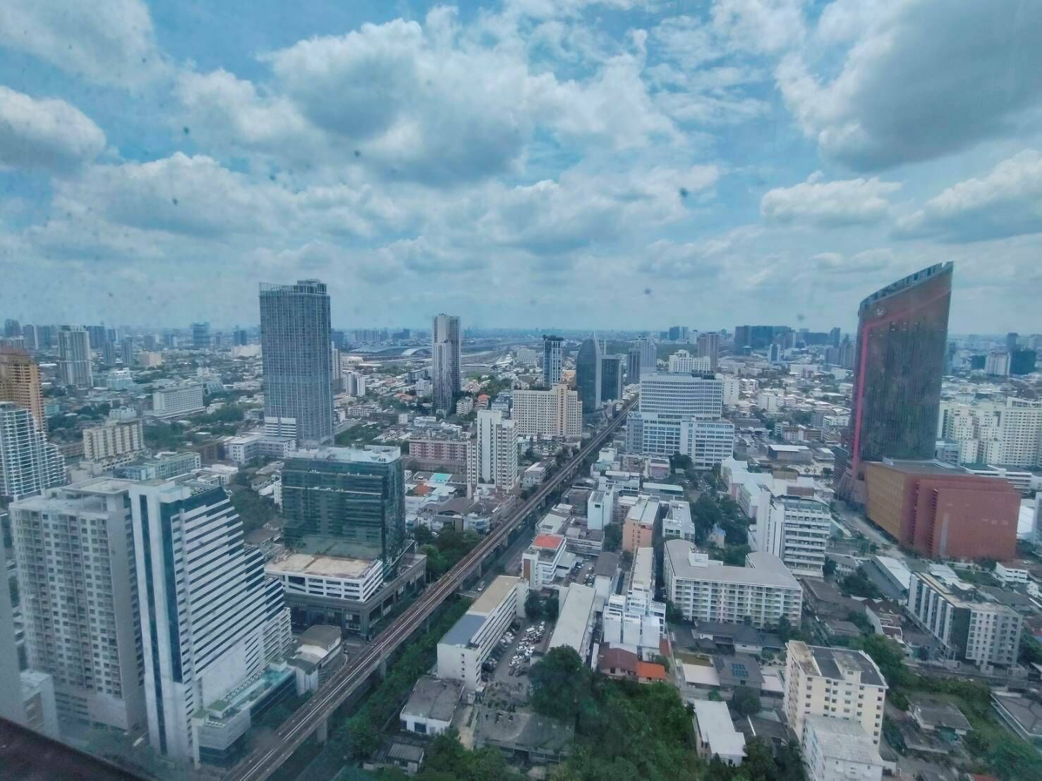 Un paisaje urbano con rascacielos, una estructura roja destacada y una autopista.