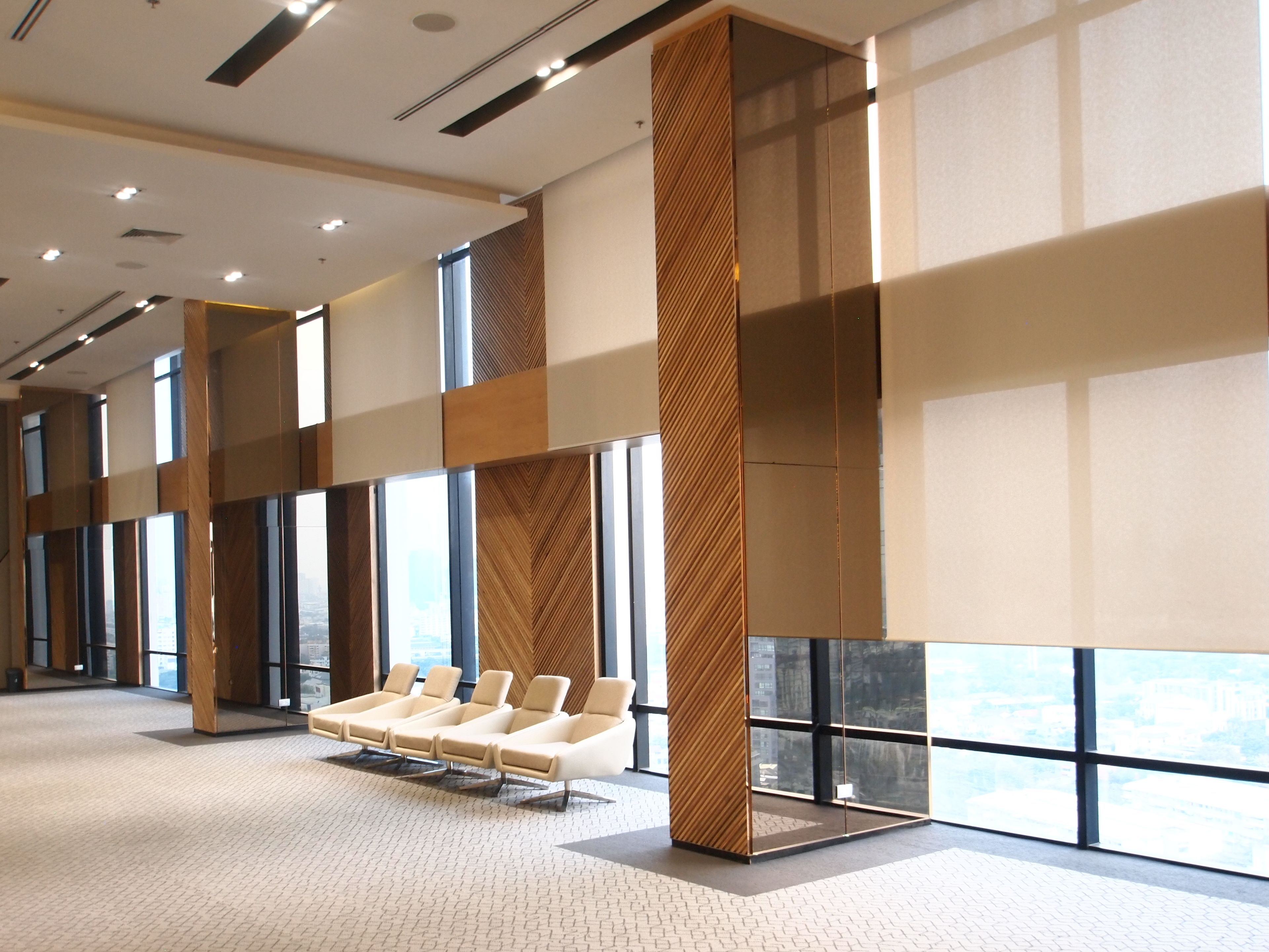Um hall amplo com design moderno, com área de estar e poltronas estofadas e um pilar decorado.