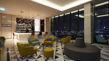 A modern hotel lobby with a bar area, seating arrangements, and a city view.