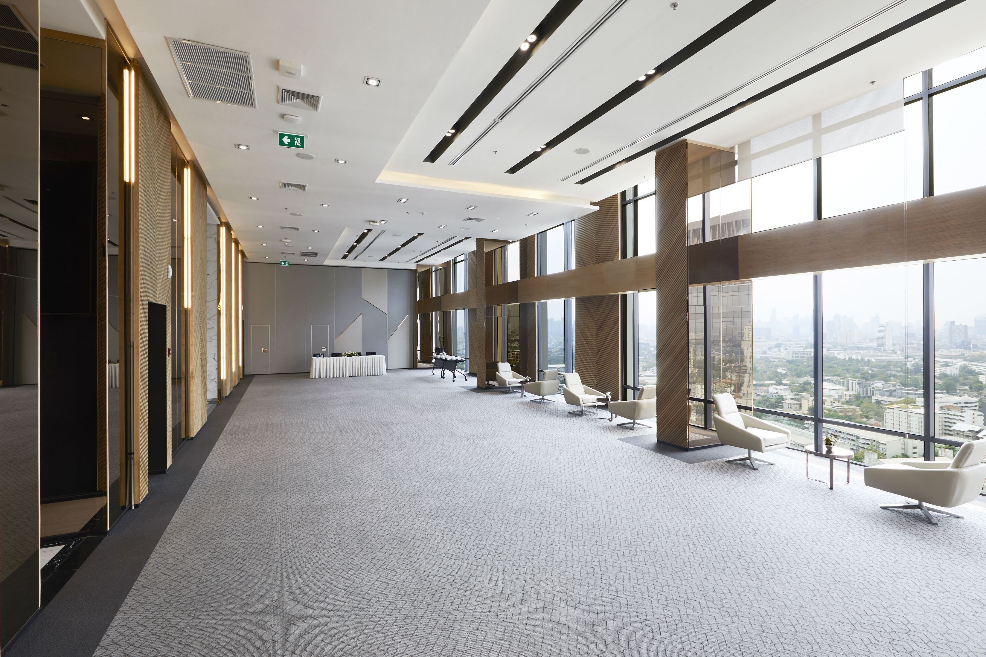 Una amplia sala de conferencias con techo alto, ventanas grandes que ofrecen vistas a la ciudad y modernas disposiciones de asientos.