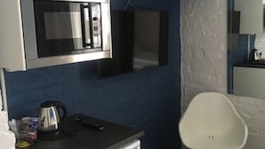 A compact kitchen with a microwave, a small refrigerator, and a white chair. - Place to Sleep Hotel Rauma (Rauma)