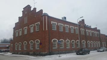 Suuri tiilinen rakennus, jossa on useita ikkunoita ja jalankulkijoiden suojatien opaste.