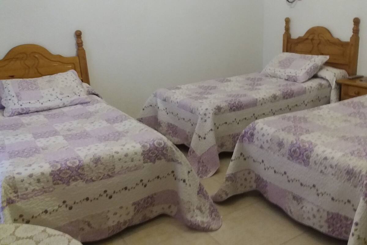 Ein Schlafzimmer mit zwei Einzelbetten, jeweils mit einem Holz-Kopfteil und einer blumengemusterten Bettdecke.
