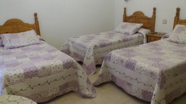 A bedroom with two single beds, each with a wooden headboard and a floral-patterned bedspread. - Hotel Covadonga (Benavente)