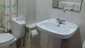 Et badeværelse med badekar, toilet og håndvask.