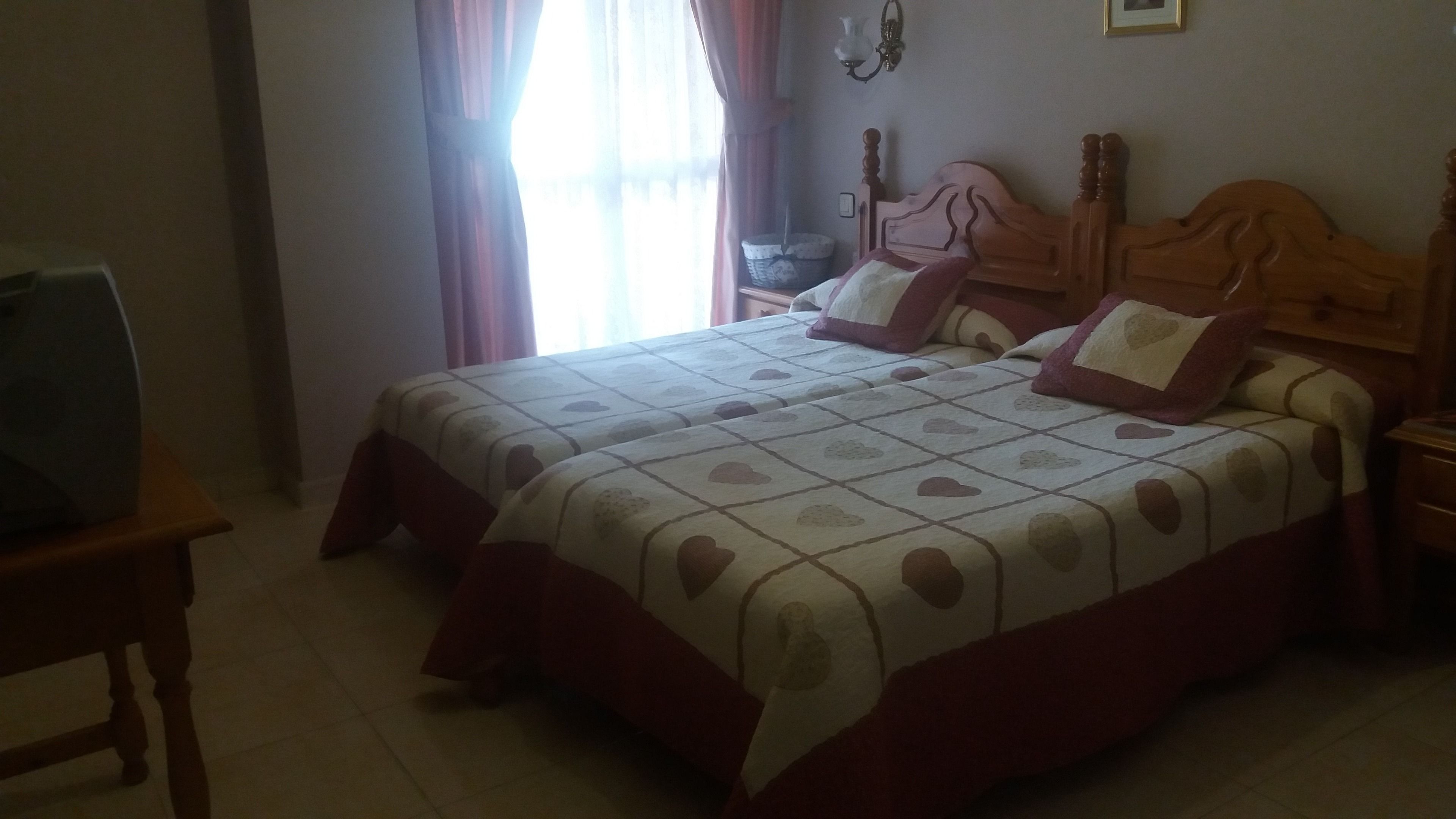 A bedroom with a bed, wooden headboard, and a nightstand.