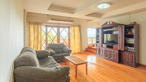 A living room with a sofa, armchair, and TV stand. - Phuripimarn Penthouse (Pak Chong)