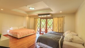 A hotel room with two beds, wooden flooring, a ceiling fan, and a large window with curtains. - Phuripimarn Penthouse (Pak Chong)