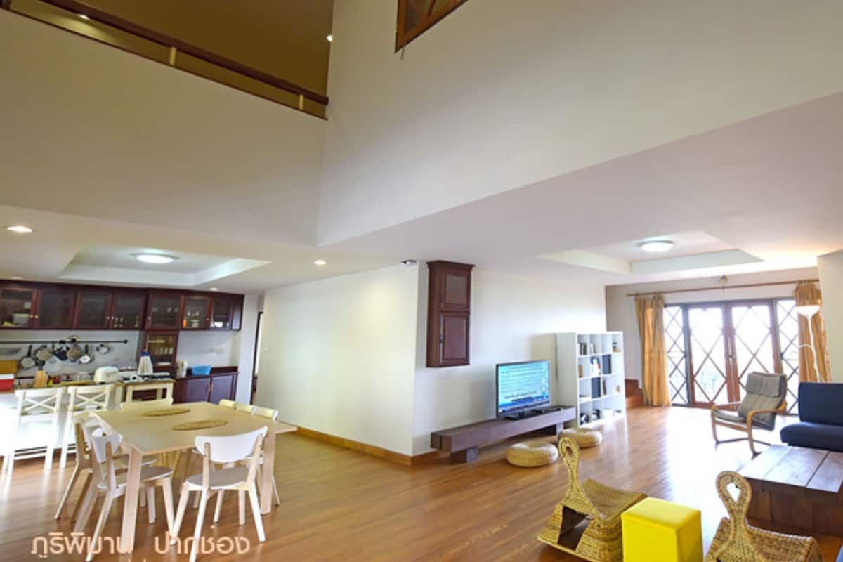 A spacious living area with a dining table, chairs, a sofa, and a television.