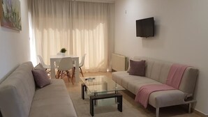 Un salon moderne avec un canapé, une table basse en verre et un coin repas comprenant une table et des chaises.