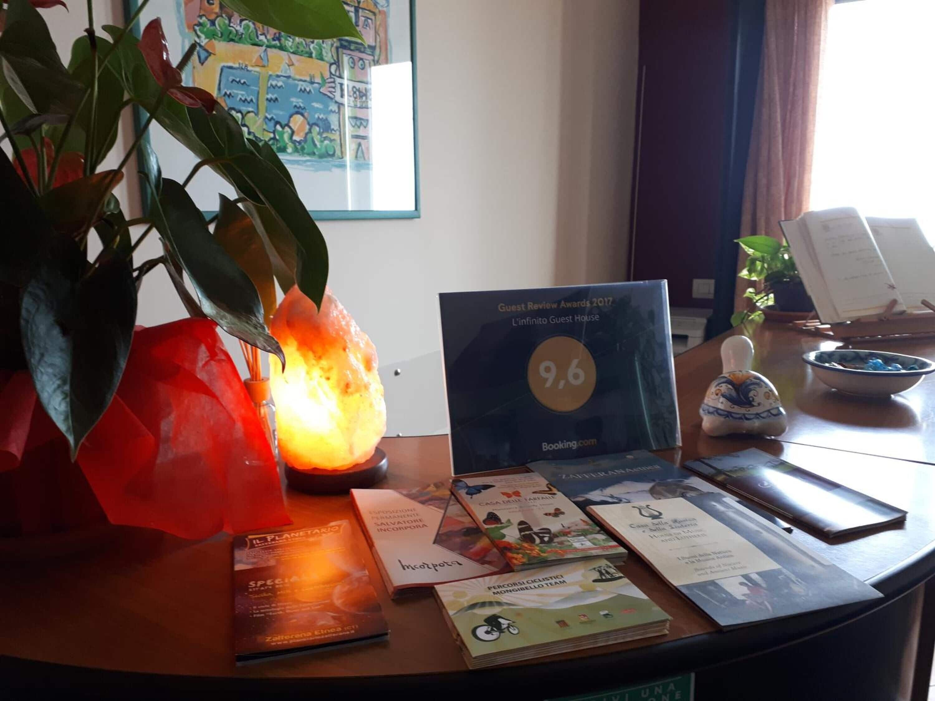 A desk with a framed award, brochures, a salt lamp, and a potted plant.