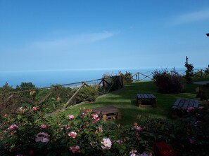 A garden with a wooden fence, a picnic table, and a view of the sea. - L'infinito (Milo)