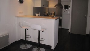 Una cocina moderna con taburetes blancos, una isla integrada y un microondas.